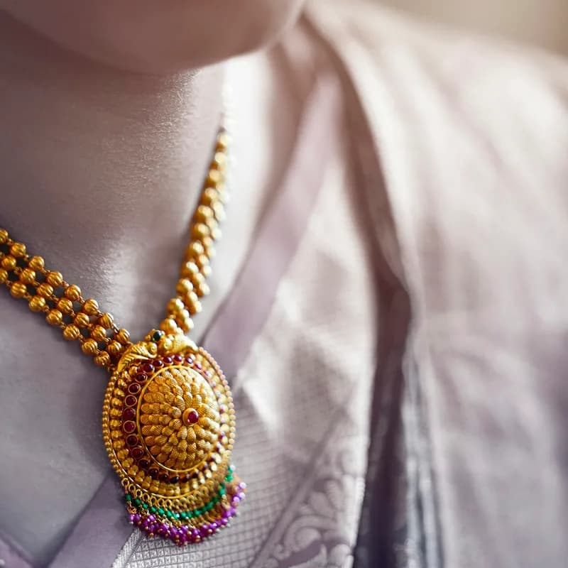 A gold pendant necklace worn at the collarbone