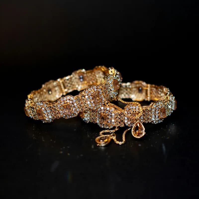 A diamond-set gold bracelet on a dark ground